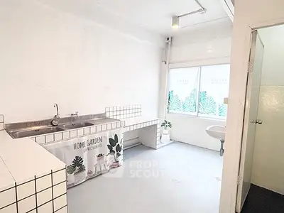Spacious minimalist kitchen with tiled countertops and large window for natural light.