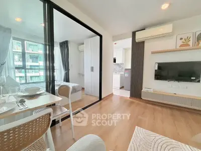Modern open-plan living room with glass partition, dining area, and view into a stylish kitchen.