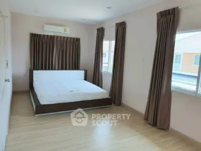 Spacious bedroom with large windows and modern bed in a well-lit room.