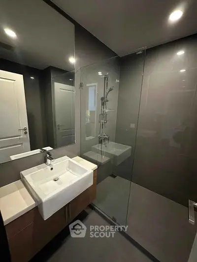 Modern bathroom with sleek glass shower and stylish sink in contemporary apartment.