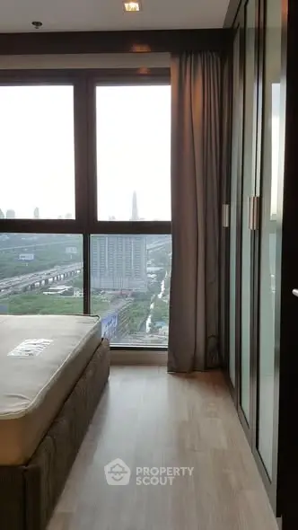 Modern bedroom with floor-to-ceiling windows offering stunning city views