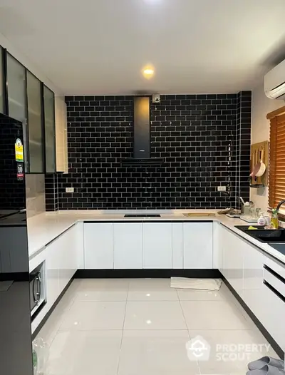 Sleek modern kitchen with high-contrast black subway tiles and white cabinetry, featuring built-in appliances and ample storage space, perfect for culinary enthusiasts.