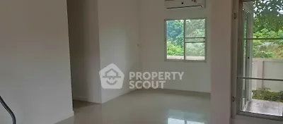Spacious empty room with large window and air conditioning, offering serene green views.