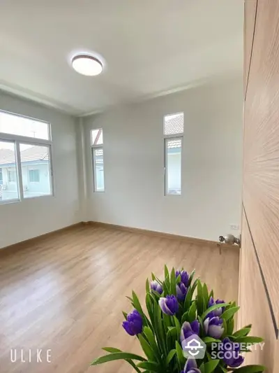 Spacious and bright unfurnished room with high ceilings, large windows, and modern laminate flooring, perfect for personalizing your dream living space.