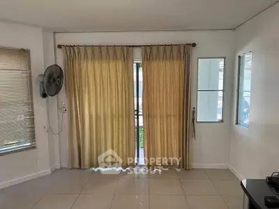 Spacious living room with large windows and neutral decor, perfect for natural light.