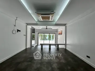 Spacious modern living room with sleek flooring and large windows offering natural light.