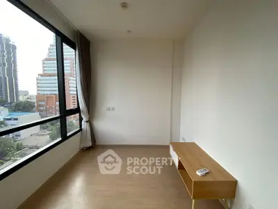 Spacious room with large window offering city view, perfect for a modern living space.
