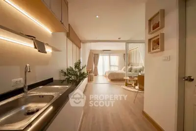 Modern open-plan apartment with sleek kitchen and cozy bedroom, featuring warm lighting and stylish decor.