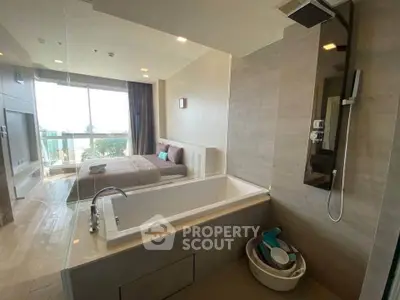 Modern bedroom with integrated bathtub and large window offering city view.