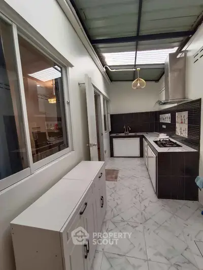 Modern kitchen with sleek design and gas stove, featuring marble flooring and ample natural light.