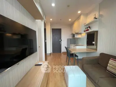 Modern living room with open kitchen, featuring sleek furniture and wooden flooring.