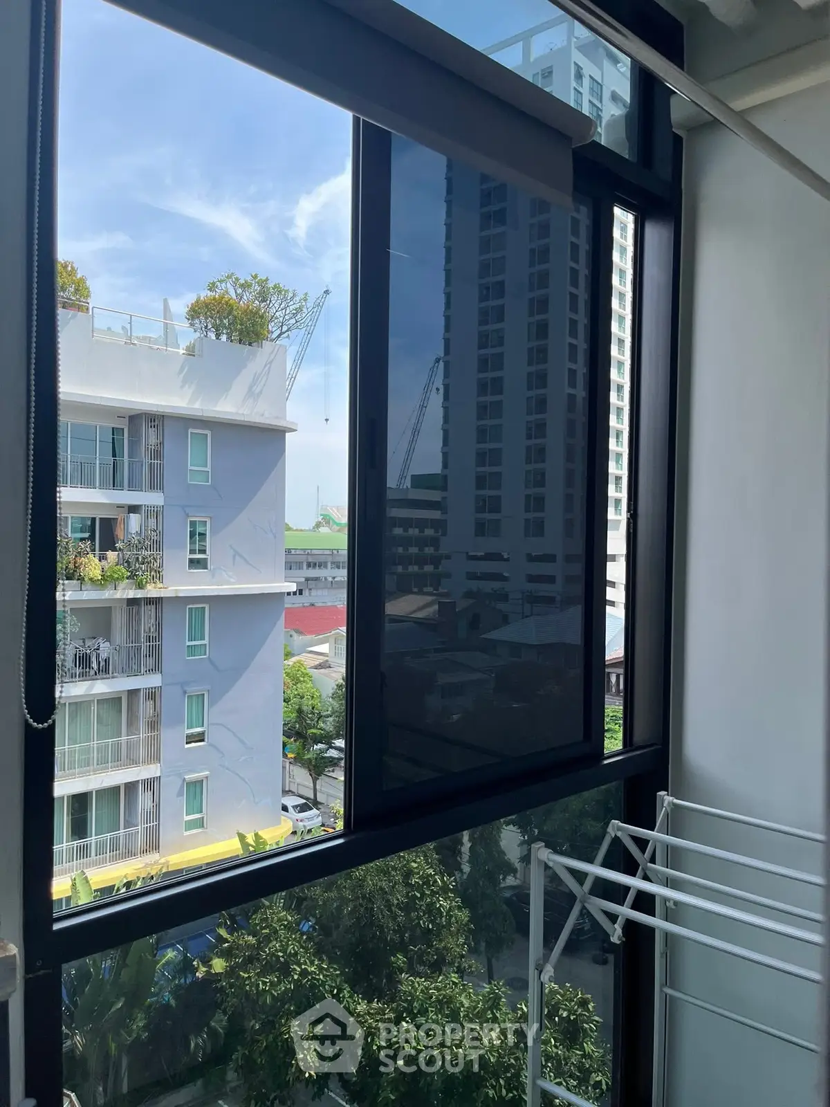 Modern apartment window with city view and laundry rack