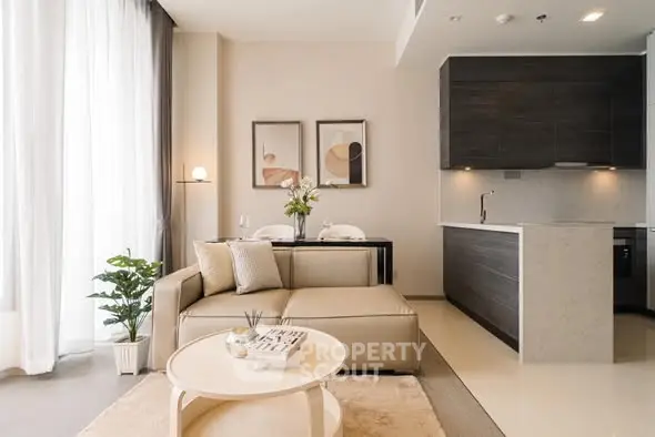 Modern living room with open kitchen, stylish decor, and natural light.