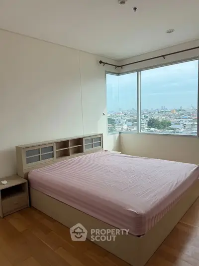 Spacious bedroom with large window offering stunning city views, featuring a cozy bed and wooden flooring.