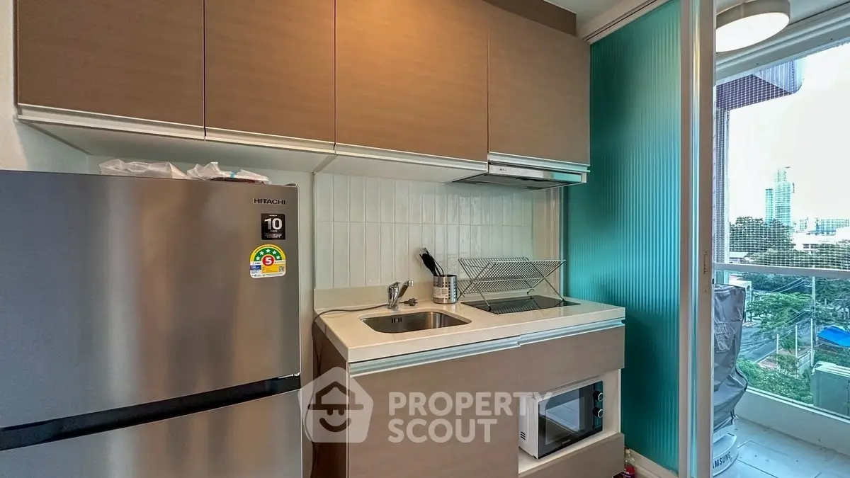 Modern compact kitchen with sleek appliances and balcony view