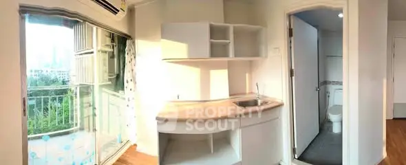 Compact kitchen with balcony view and adjacent bathroom in modern apartment