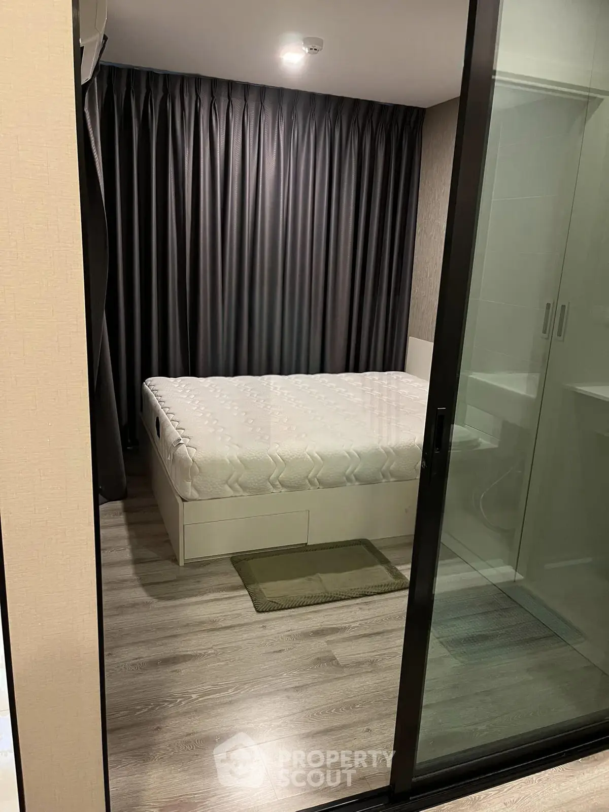 Modern bedroom with glass partition and elegant curtains in a stylish apartment.
