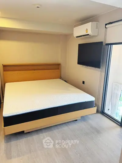 Modern bedroom with sleek design, featuring a comfortable bed, wall-mounted TV, and air conditioning.