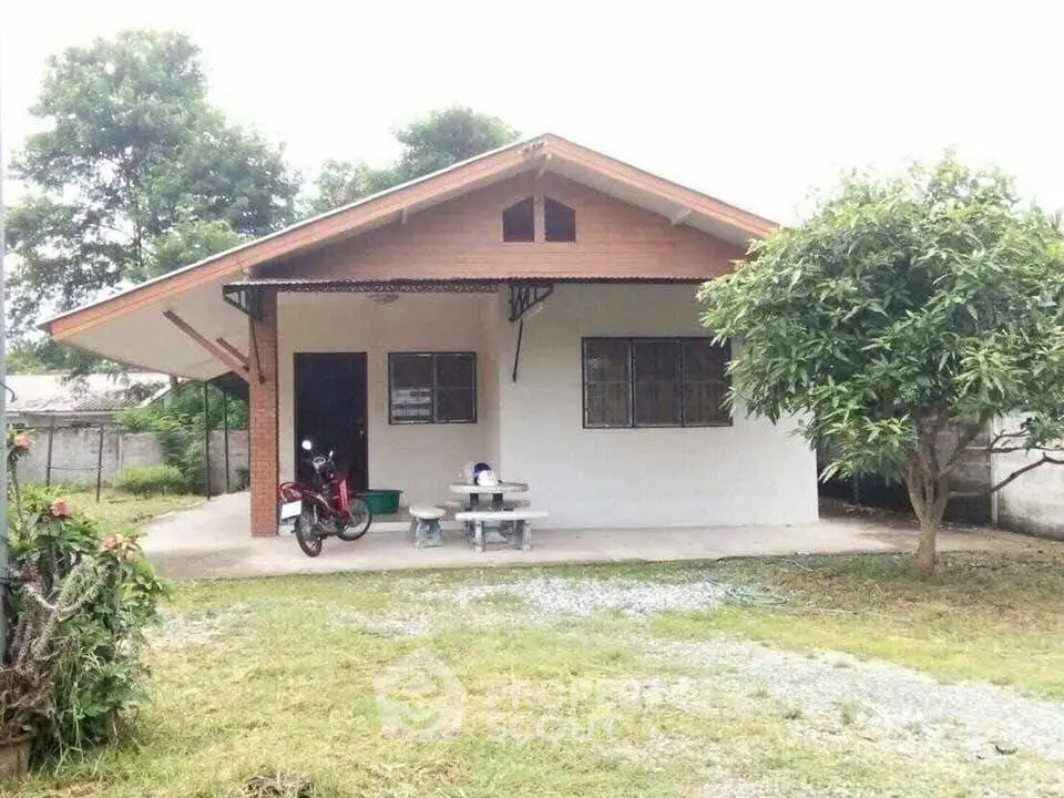 Charming single-story house with front porch and lush greenery, perfect for serene living.
