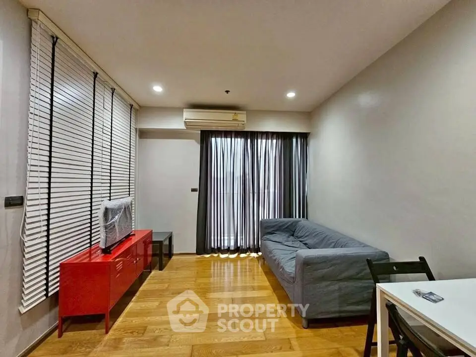 Modern living room with sleek wooden flooring, stylish furniture, and natural light from large windows.