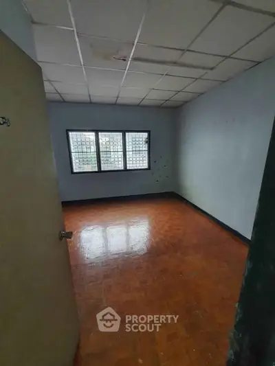 Spacious empty room with wooden flooring and large windows, ideal for customization.