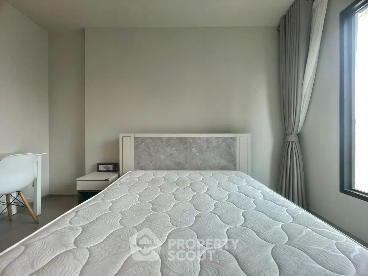 Modern bedroom with minimalist design and large window for natural light.