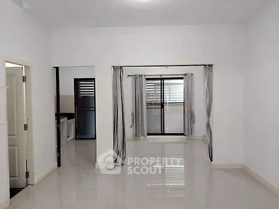 Spacious living room with large windows and glossy tiled floors in modern apartment.
