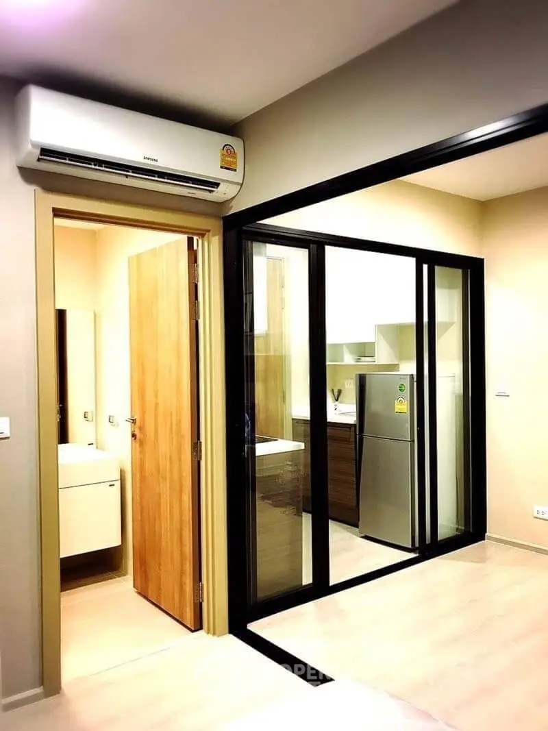Modern apartment interior with sleek kitchen and air conditioning unit, featuring sliding glass doors.