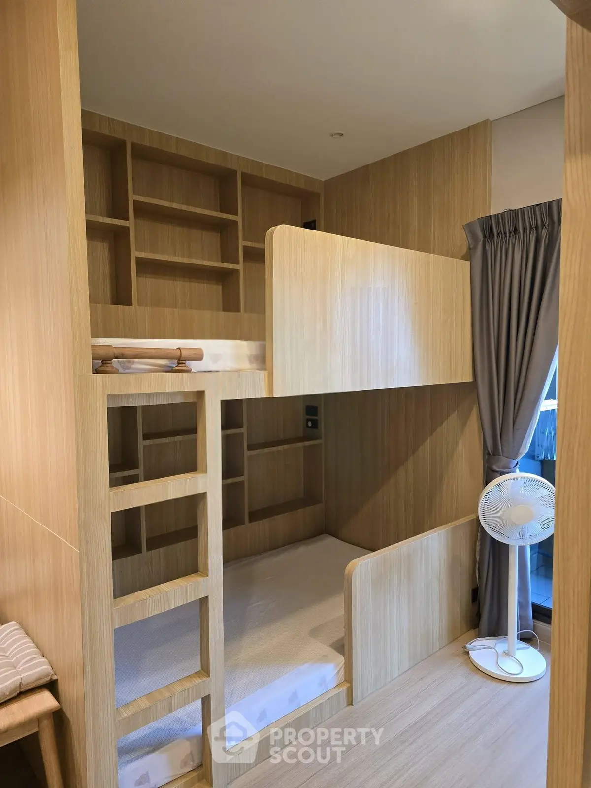Modern wooden bunk bed in cozy bedroom with built-in shelves and natural light.