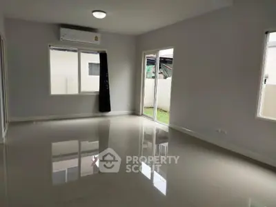 Spacious empty living room with glossy tiled floors and large windows