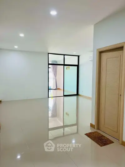 Spacious modern living room with glossy tiled floors and large windows for natural light.