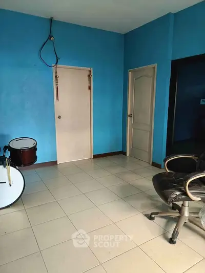 Spacious room with blue walls, tiled floor, and office chair, ideal for home office or creative space.