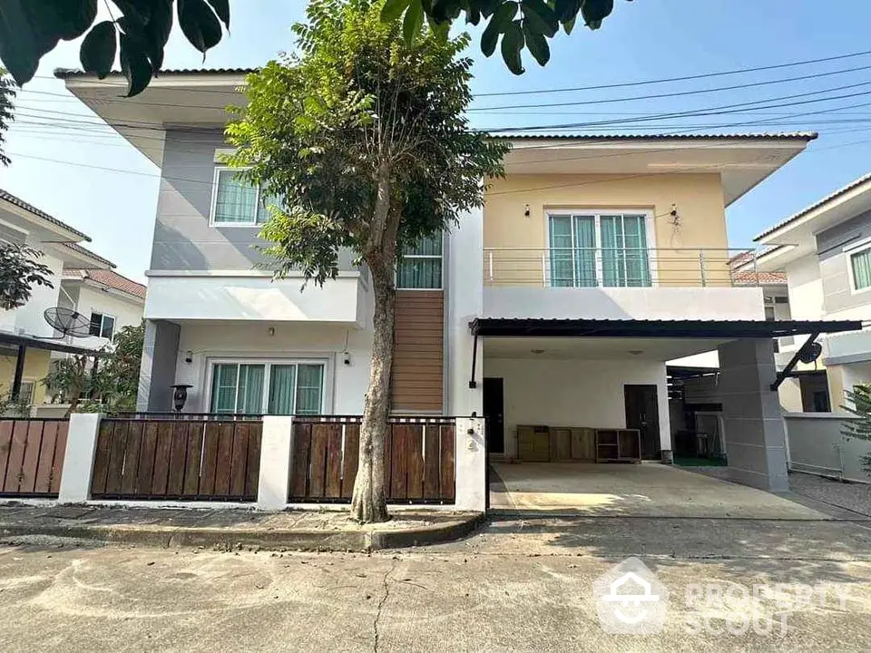 Modern two-story house with balcony and driveway in a serene neighborhood.