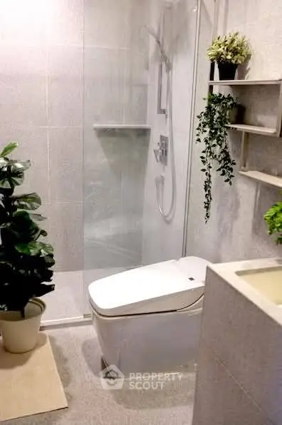 Modern bathroom with sleek fixtures and lush greenery accents.