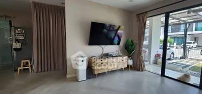 Modern living room with wall-mounted TV and large window view of driveway.