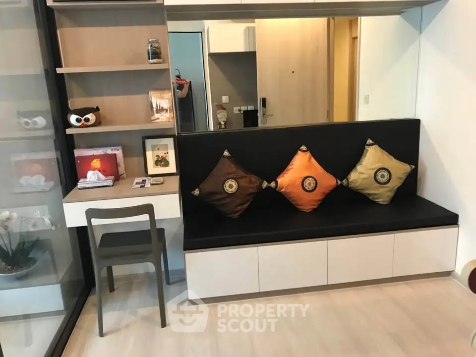 Modern living room with stylish seating and decorative pillows, featuring a compact study area.