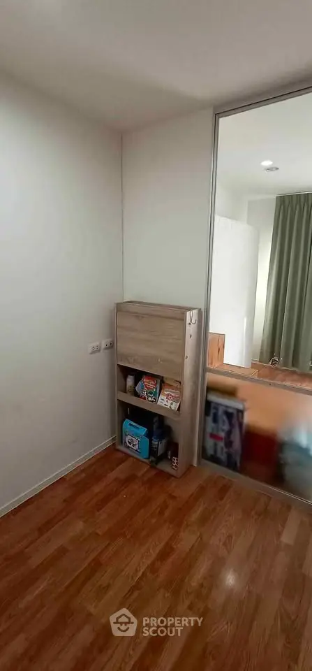Compact room with wooden flooring and a small storage shelf, ideal for cozy living spaces.