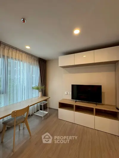 Modern living room with sleek TV unit and large window for natural light.