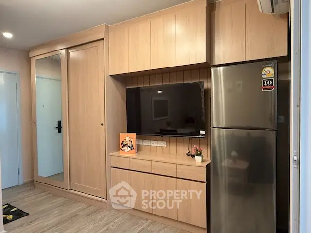 Modern living room with built-in wooden cabinets and stainless steel fridge