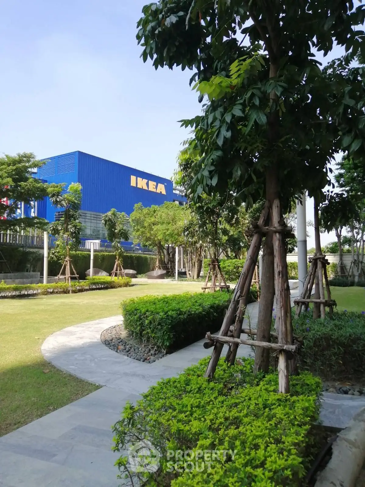 Lush green garden with pathway leading to a large blue building