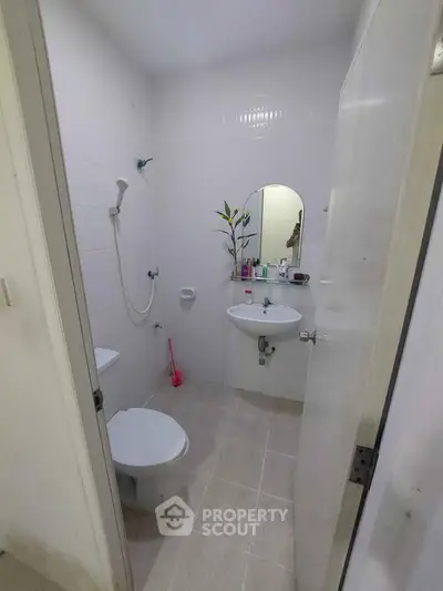 Compact bathroom with shower, sink, and toilet in minimalist design.