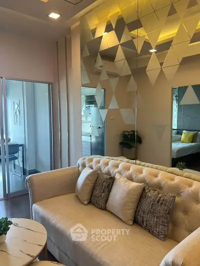 Stylish living room with modern decor and mirrored wall, featuring a plush sofa and elegant design.