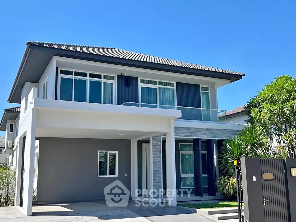 Modern two-story house with sleek design and spacious driveway under clear blue sky.