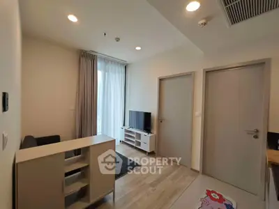Modern living room with TV and natural light, featuring minimalist design and cozy atmosphere.