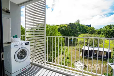 Charming balcony with lush green view and modern washing machine setup.