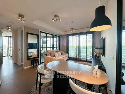 Modern living room with open layout and stylish decor, featuring large windows and a cozy seating area.