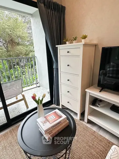 Charming living room with balcony view, featuring stylish furniture and decor.