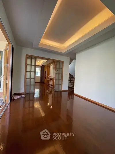 Spacious living room with wooden flooring and modern ceiling design