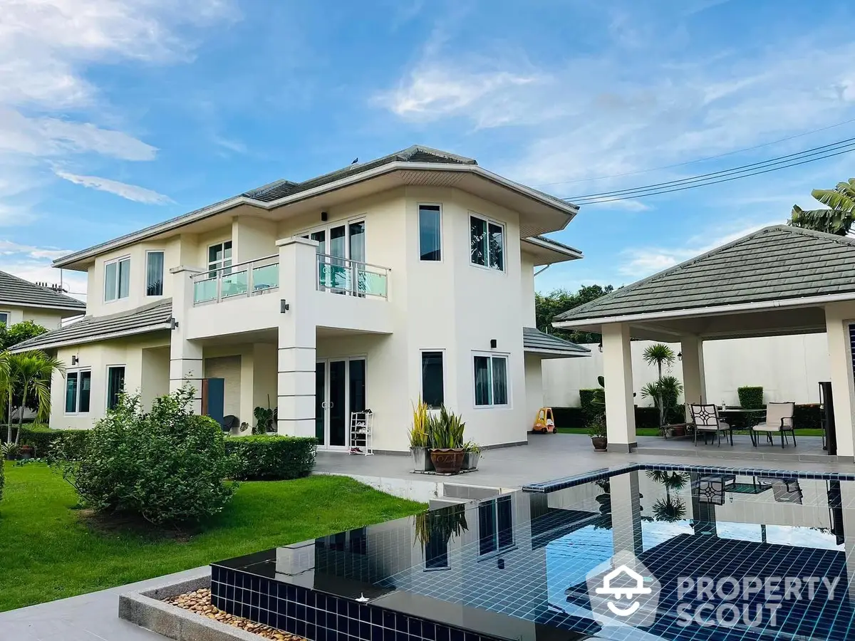 Luxurious two-story villa with a sparkling pool and lush garden, featuring a spacious patio and modern architecture in a serene neighborhood.