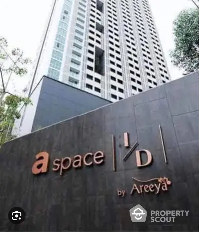 Modern high-rise condominium tower with a stylish entrance sign, showcasing urban living in a prime location with lush greenery.